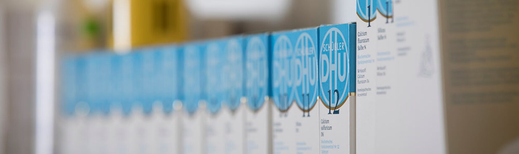 Reihen von homöopathischen Produkten mit blauen Etiketten sind in einem Regal ordentlich aufgereiht.