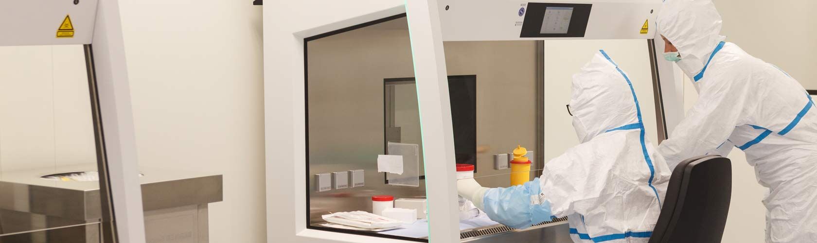 Zwei Personen arbeiten im Reinraumlabor der Beilharz Apotheke in Isny unter dem Vier-Augen-Prinzip in Schutzanzügen.